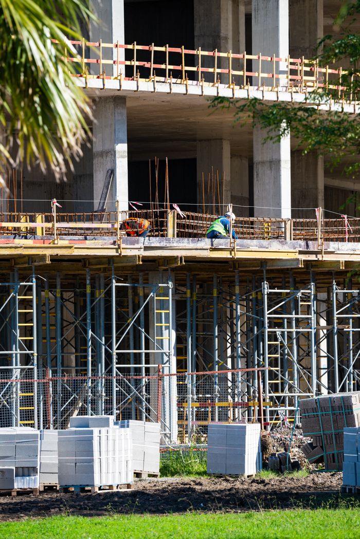 services-01 Construction workers on site with scaffolding and materials in sunlight.
