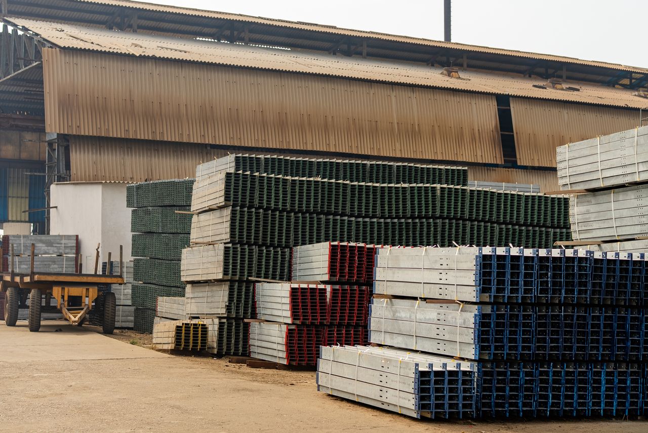 pexels photo 36003983 Outdoor view of an industrial warehouse with multiple stacks of metal beams and pallets.